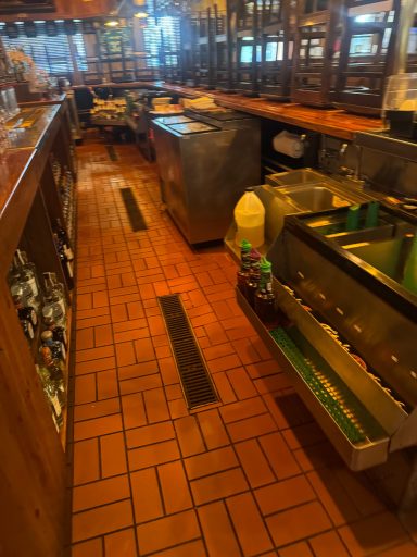 Empty restaurant interior with wooden counters and tiled flooring, showing kitchen equipment.